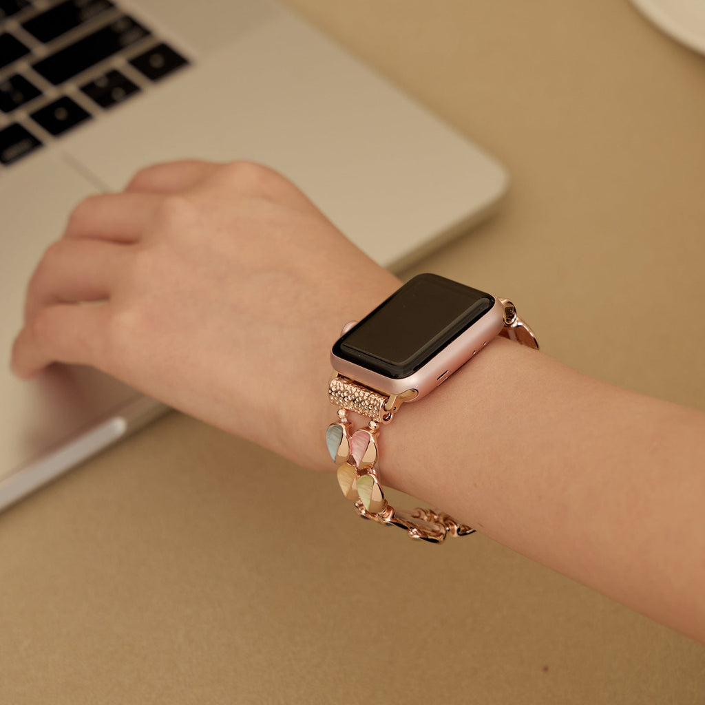 Bracelet Apple Watch modèle Raquel rose avec pétales scintillants en métal délicat, porté au poignet féminin.