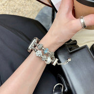 Bracelet double-rangs pour Apple Watch en perles blanches et bleues avec charms argentés sur poignet.