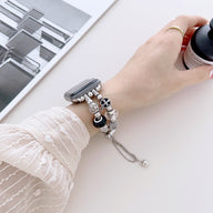 Bracelet double-rangs rose pour Apple Watch avec breloques argentées variées sur poignet féminin.