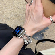 Bracelet Apple Watch double-rangs rose avec multiples charms argentés sur poignet féminin.