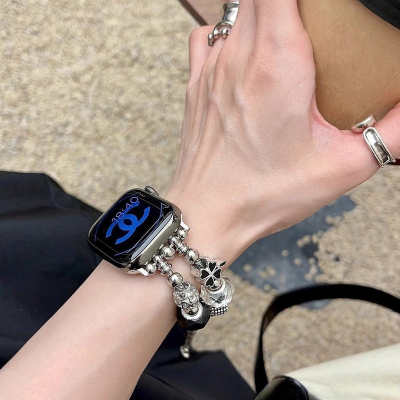 Bracelet Apple Watch double-rangs rose avec multiples charms argentés sur poignet féminin.