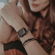 Bracelet Apple Watch noir en acier inoxydable, modèle Minoa, porté au poignet féminin.