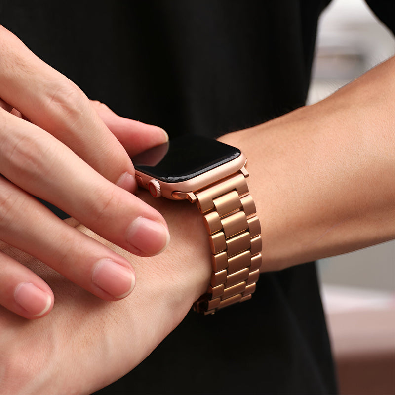 Bracelet Apple Watch en acier inoxydable or rosé avec maillons larges porté au poignet homme.
