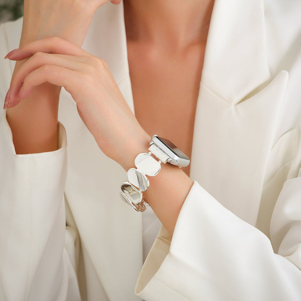 Bracelet Apple Watch Lidia en alliage métallique argenté avec maillons ovales, porté par une femme en veste blanche.