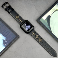 Bracelet Apple Watch en cuir noir avec rivets dorés décoratifs et coutures contrastantes blanches.