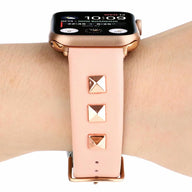 Bracelet en cuir rose pâle pour Apple Watch avec trois rivets carrés dorés.