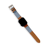 Bracelet Apple Watch en cuir marron et denim bleu clair, boucle argentée, couture orange visible.