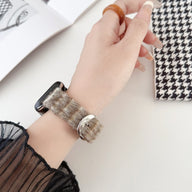 Bracelet Apple Watch en laine gris à motif torsadé avec boucle en cuir clair sur poignet femme.