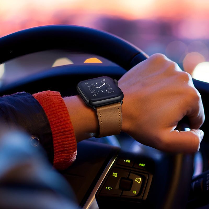 Bracelet Apple Watch en cuir cognac, style mixte, porté au poignet dans une voiture au crépuscule.