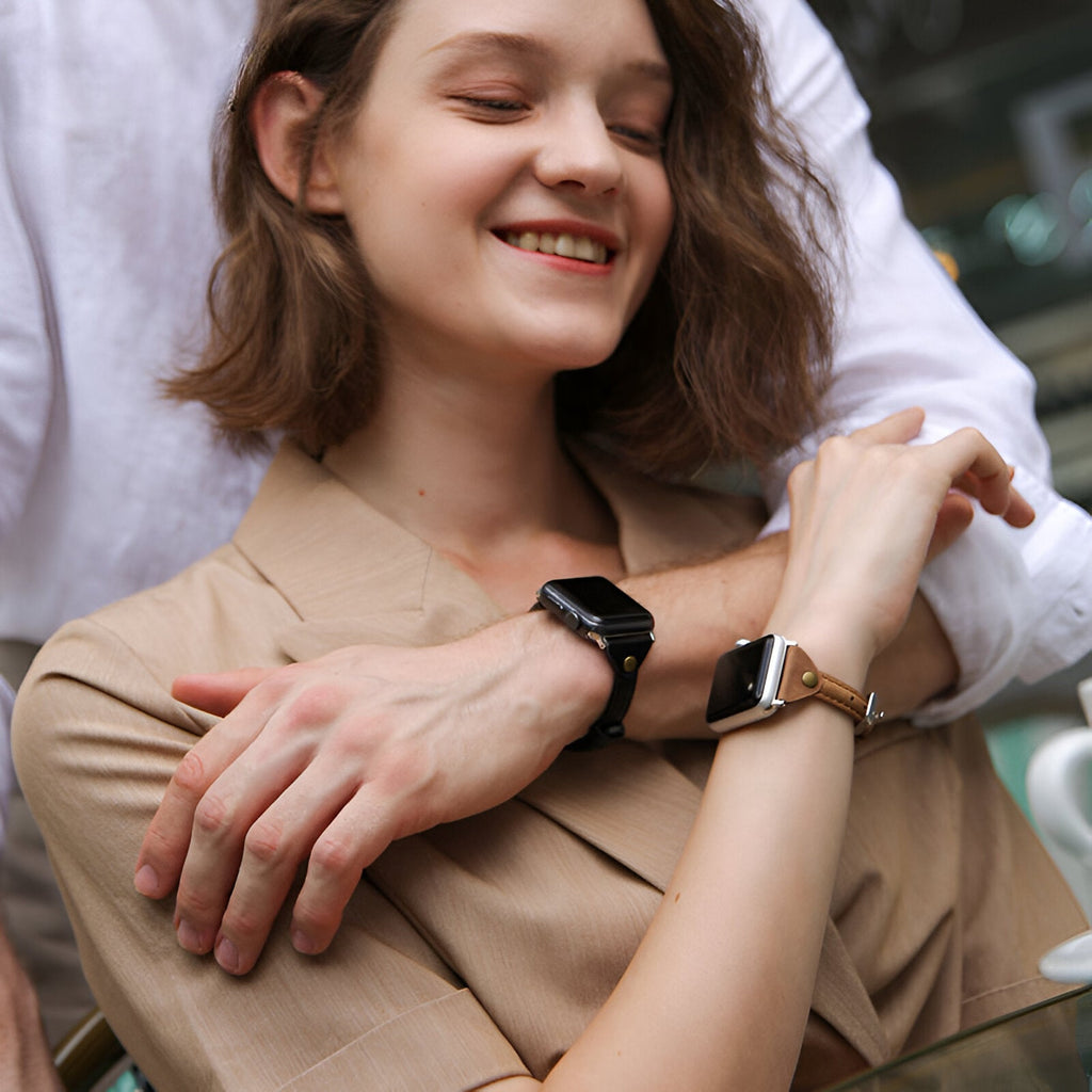 Bracelet en cuir noir pour Apple Watch taille moyenne porté par un homme et bracelet en cuir marron clair porté par une femme.