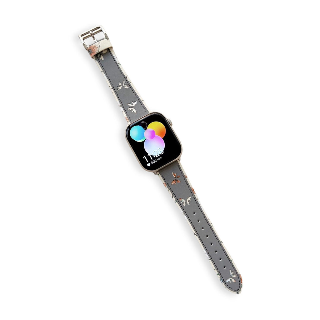 Bracelet Apple Watch en cuir gris avec motif papillons délicats, boucle argentée brillante.