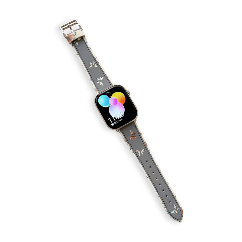Bracelet Apple Watch en cuir gris avec motif papillons délicats, boucle argentée brillante.