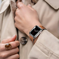 Bracelet Apple Watch marron en cuir perforé respirant avec boucle argentée, porté au poignet féminin.