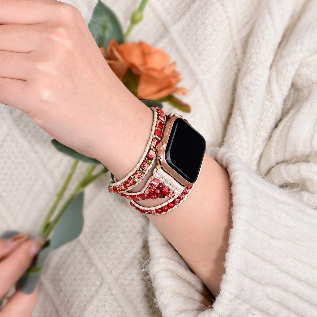 Bracelet Apple Watch en jaspe rouge multirang avec perles rondes sur poignet féminin en pull blanc côtelé.