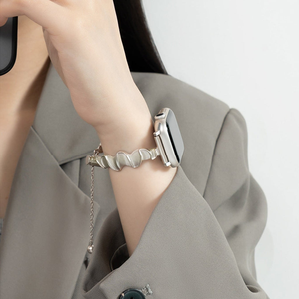 Bracelet torsadé en métal argenté pour Apple Watch porté sur un poignet féminin.