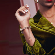 Bracelet Apple Watch métal torsadé or rose avec chaînette d'ajustement porté sur poignet femme robe velours vert.