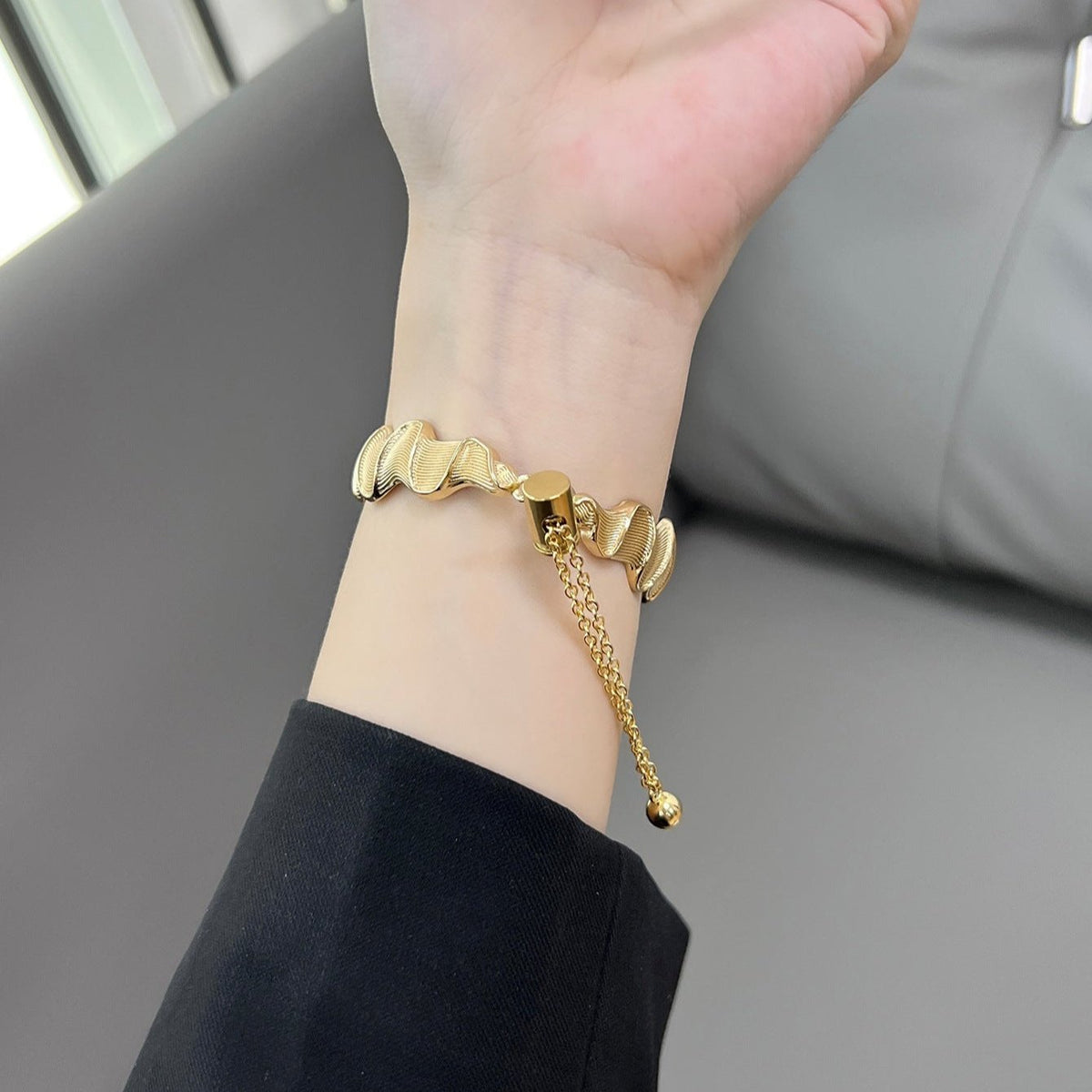 Bracelet Apple Watch en métal torsadé or avec chaîne réglable porté au poignet féminin.