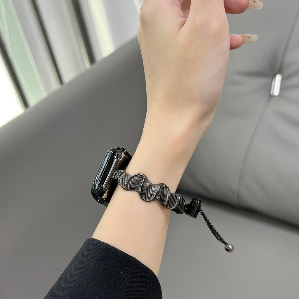 Bracelet Apple Watch métal torsadé noir avec cordon ajustable porté au poignet féminin.