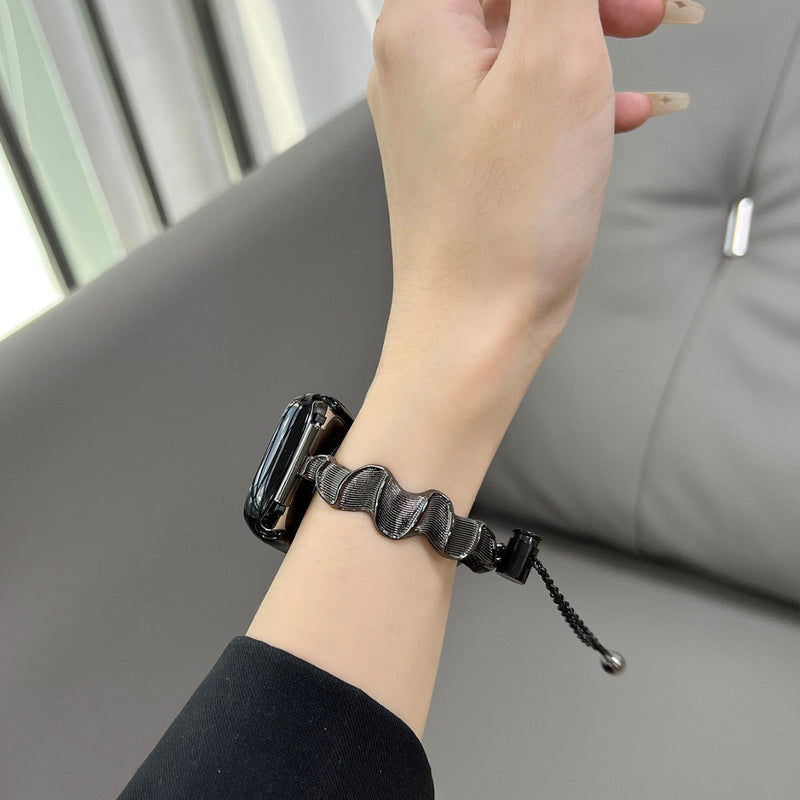 Bracelet Apple Watch métal torsadé noir avec cordon ajustable porté au poignet féminin.