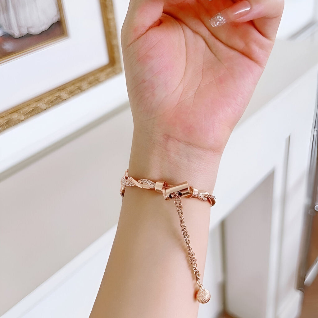 Bracelet Apple Watch torsadé en métal or rosé avec chaîne ajustable sur poignet féminin.