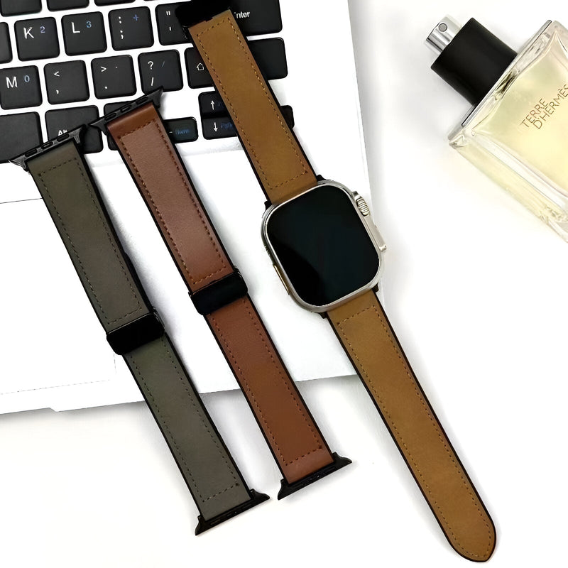 Bracelet Apple Watch en microfibre marron clair avec raccords noirs sur montre carrée argentée, posé sur clavier et à côté.