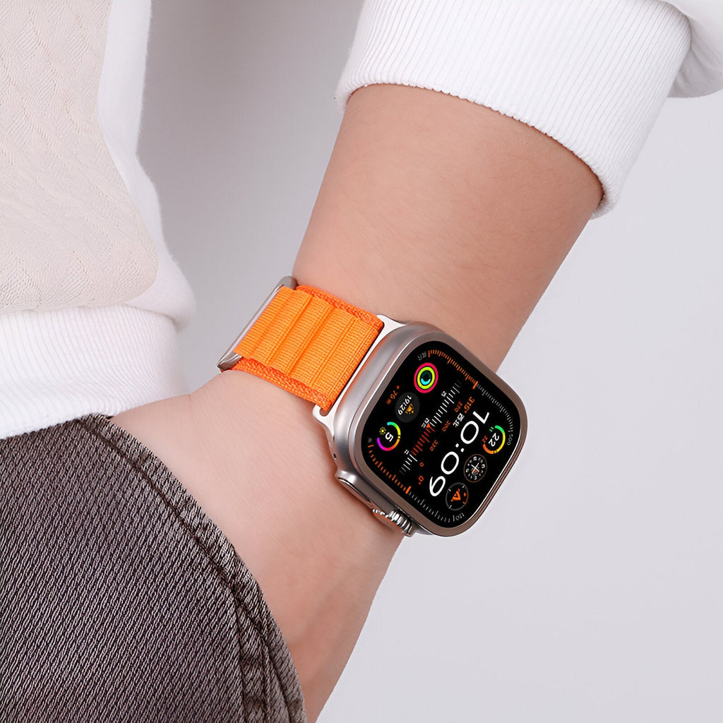 Bracelet Apple Watch en nylon orange à boucle alpine portée au poignet, style sportif et ajusté.