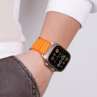 Bracelet Apple Watch en nylon orange à boucle alpine portée au poignet, style sportif et ajusté.