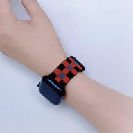 Bracelet Apple Watch en nylon à carreaux rouges et noirs, style mixte, fermé au poignet.