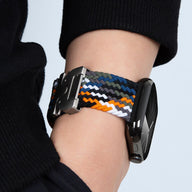 Bracelet Apple Watch en nylon tressé multicolore avec boucle tactique noire, porté au poignet.