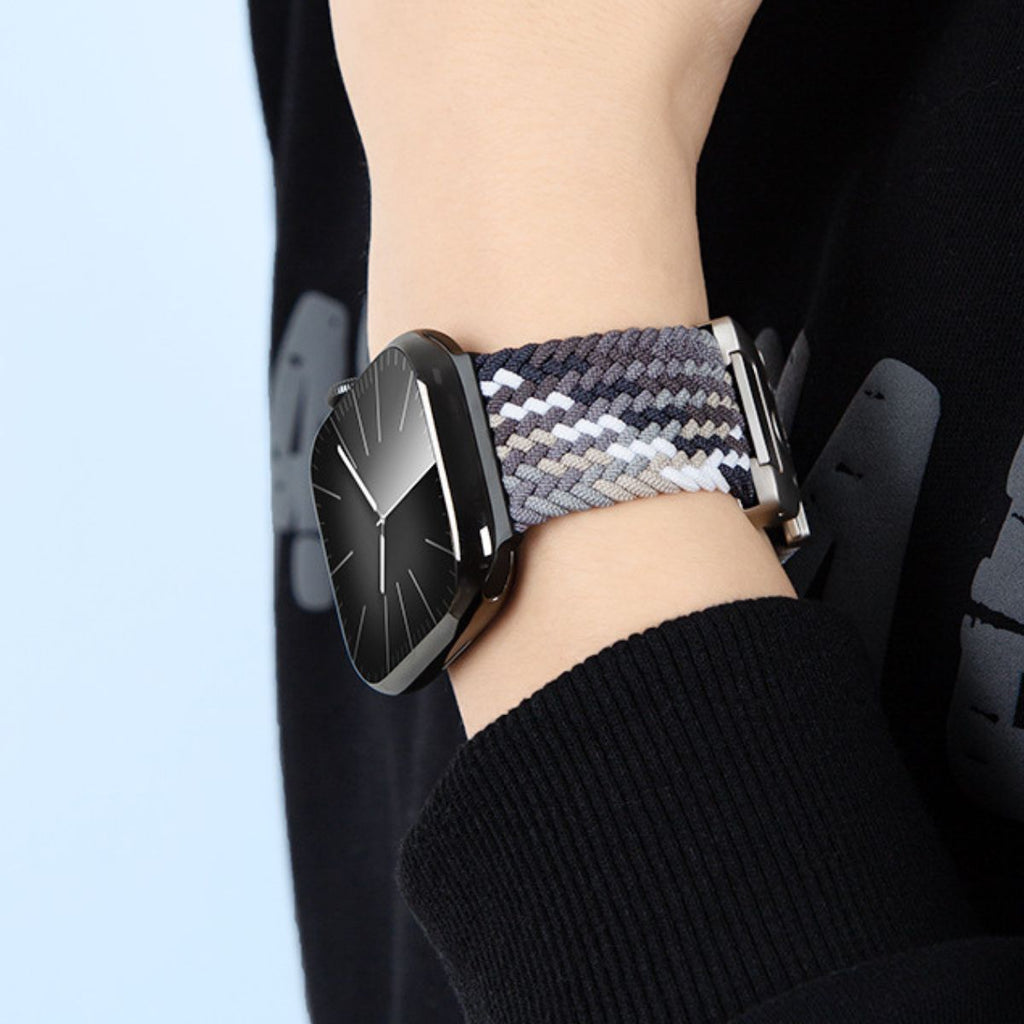 Bracelet Apple Watch en nylon tressé gris et bleu avec boucle métallique noire, porté au poignet.