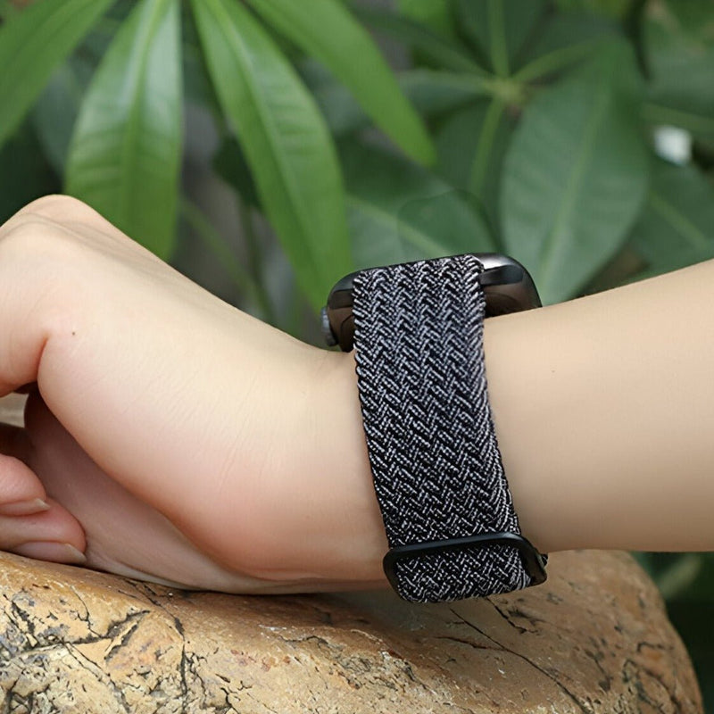 Bracelet en nylon gris tressé pour Apple Watch, style unisexe, porté au poignet.