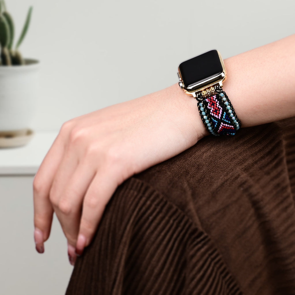 Bracelet Apple Watch en nylon noir avec motif cristaux colorés porté au poignet féminin.