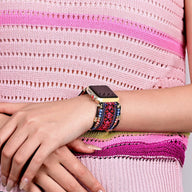 Bracelet Apple Watch en nylon rouge avec cristaux multicolores, motif ethnique, porté au poignet féminin.