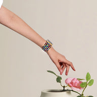 Bracelet Apple Watch multicolore en nylon tressé avec détails en cristal, porté au poignet femme.