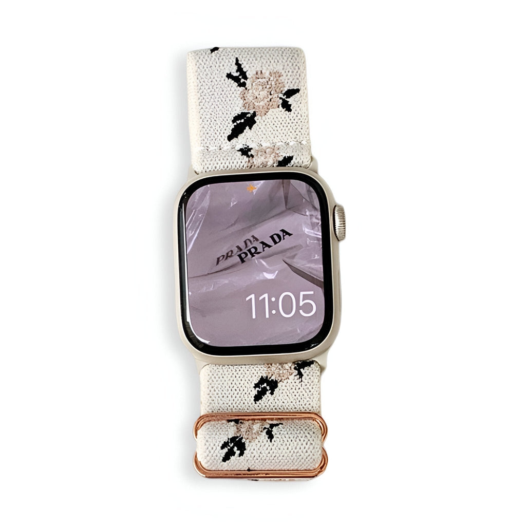 Bracelet Apple Watch en nylon blanc avec motifs floraux roses et verts, boucle cuivrée élégante.