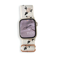 Bracelet Apple Watch en nylon blanc avec motifs floraux roses et verts, boucle cuivrée élégante.
