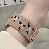 Bracelet Apple Watch en nylon beige à motifs floraux blancs et noirs, boucle dorée rose.
