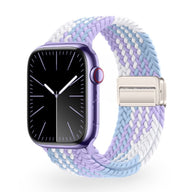 Bracelet Apple Watch en nylon tressé violet, blanc et bleu clair avec fermeture métallique argentée.