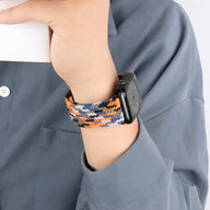Bracelet Apple Watch en nylon tressé orange, jaune, noir, et blanc portée au poignet.