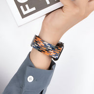 Bracelet Apple Watch Nyxan en nylon tressé orange, bleu, noir et blanc pour poignet moyen.