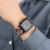 Bracelet Apple Watch en nylon orange, noir et blanc avec boucle noire sur poignet, style sportif.