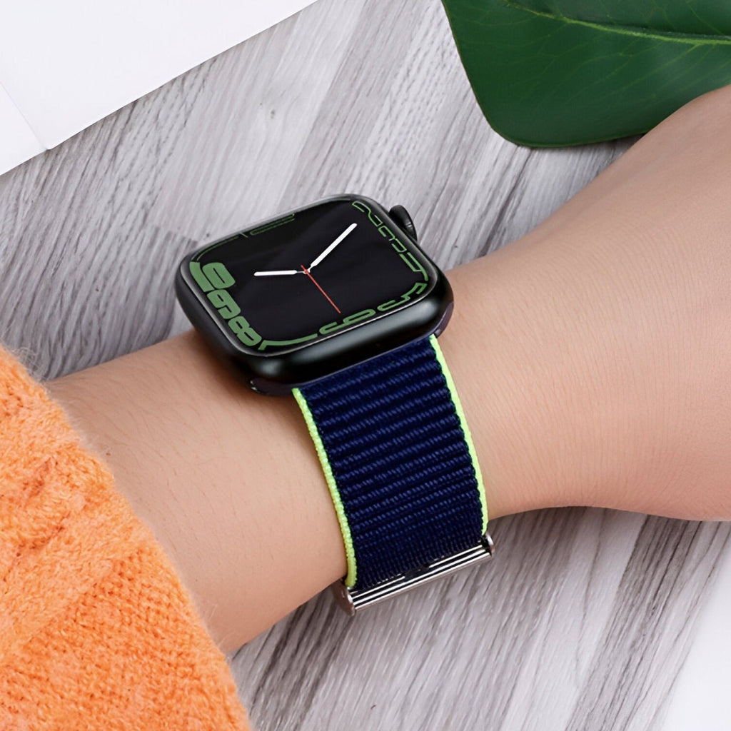 Bracelet Apple Watch en nylon bleu marine avec bordure vert clair porté au poignet.
