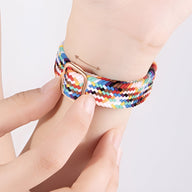 Bracelet Apple Watch Jax multicolore en nylon tressé avec boucle argentée porté au poignet féminin.