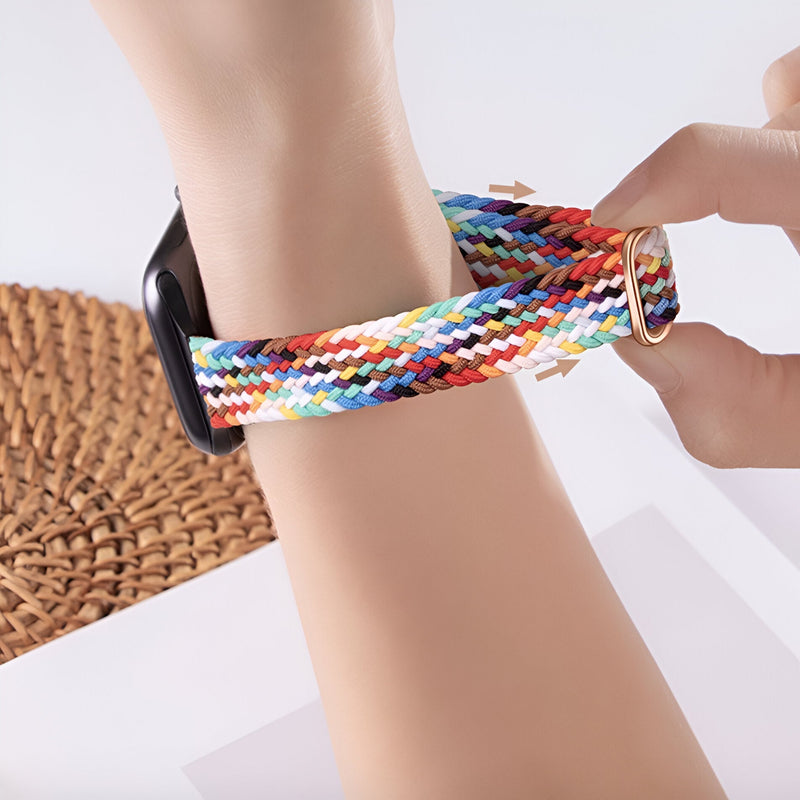 Bracelet Apple Watch en nylon multicolore avec boucle argentée sur poignet féminin.