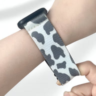 Bracelet Apple Watch en nylon gris à motif taches noires porté au poignet, boucle noire.