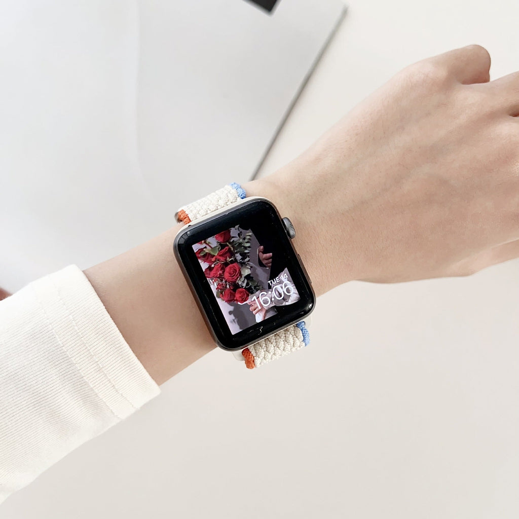 Bracelet Apple Watch en nylon blanc tressé, pour femme, porté au poignet avec montre noire.