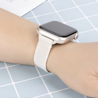 Bracelet Apple Watch en nylon tissé beige clair, modèle Azura, porté au poignet féminin.