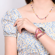 Bracelet Apple Watch rose en pierre de cristal avec détails multicolores porté au poignet féminin.