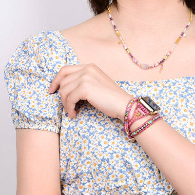 Bracelet Apple Watch rose en pierre de cristal avec détails multicolores porté au poignet féminin.