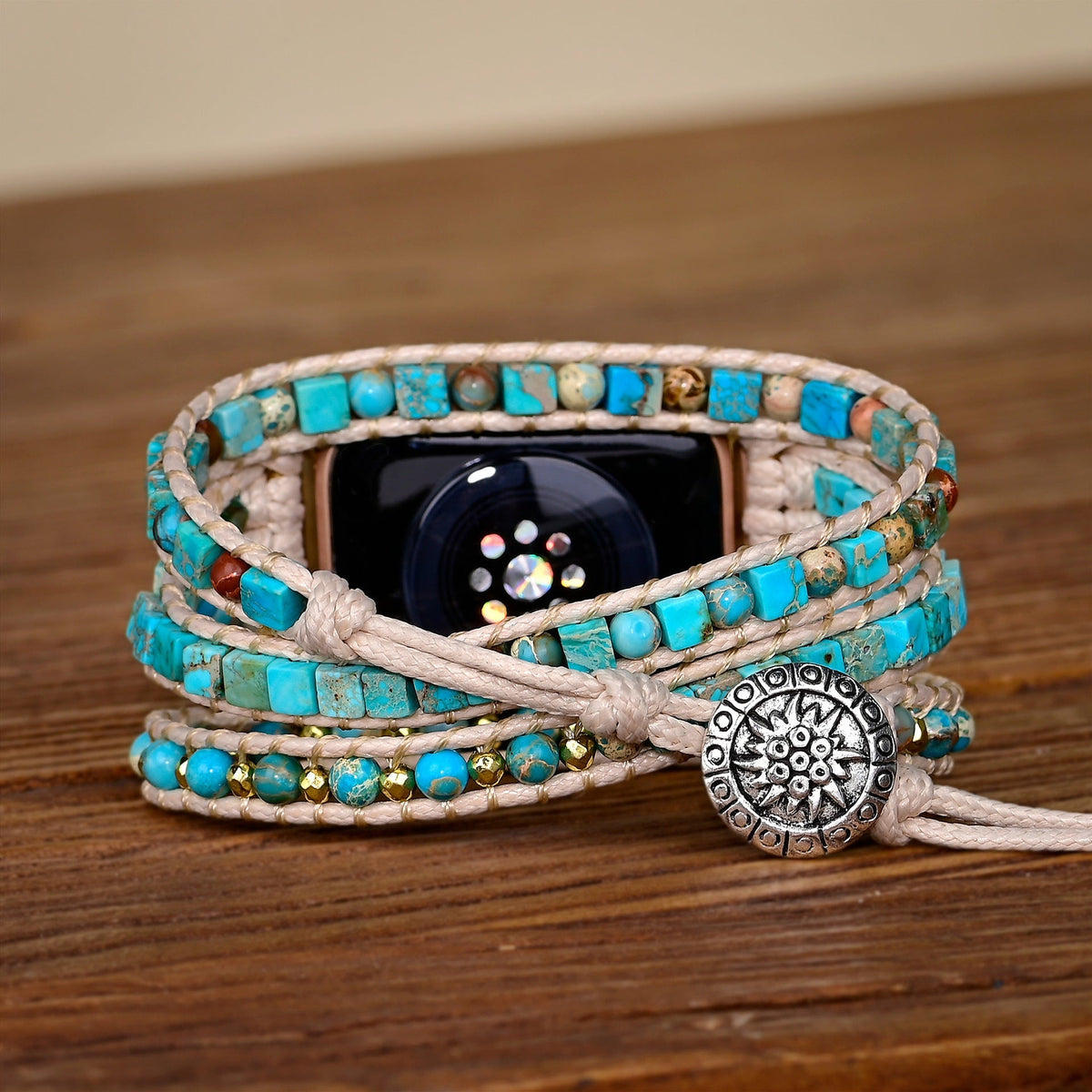 Bracelet en pierre turquoise pour Apple Watch avec fermeture bouton en métal argenté sur fond bois.